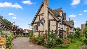 Een traditioneel gebouw in Tudor-stijl, met een bord dat aangeeft dat hier een Fleet Inn gevestigd is, met kamers, lakei's en bier.