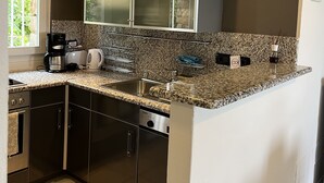 A modern kitchen with granite countertops, stainless steel appliances, and a large window providing natural light. - Apartment with garden and wonderful lake view (Bardolino)