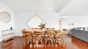 Een eetruimte met een houten tafel en stoelen, een decoratieve spiegel en een moderne airconditioning.