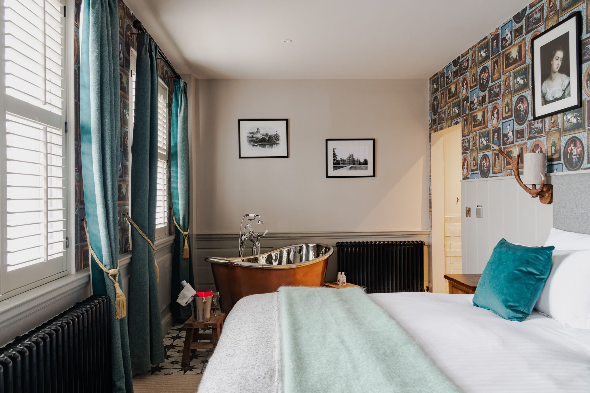 Une chambre d’hôtel avec un grand lit, une baignoire et un mur décoré de tableaux encadrés.