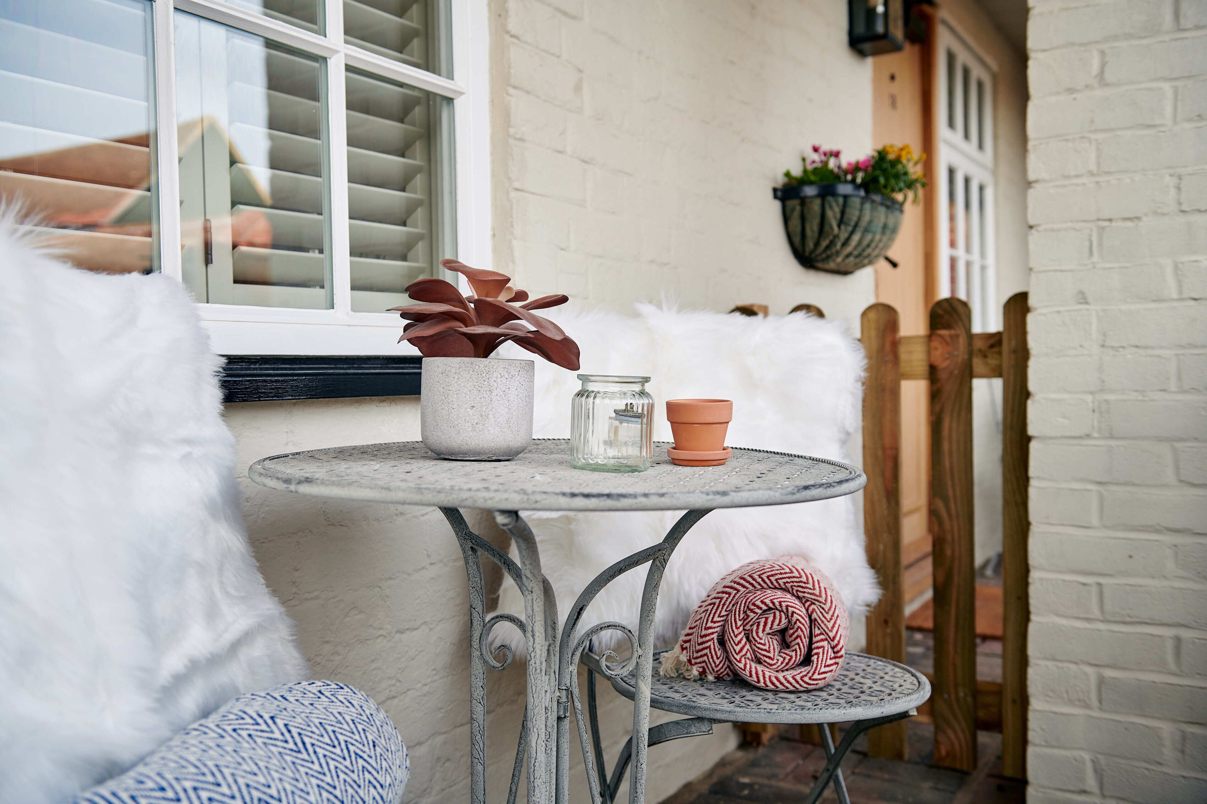 A small round table with a potted plant, a glass jar, and a terracotta pot.