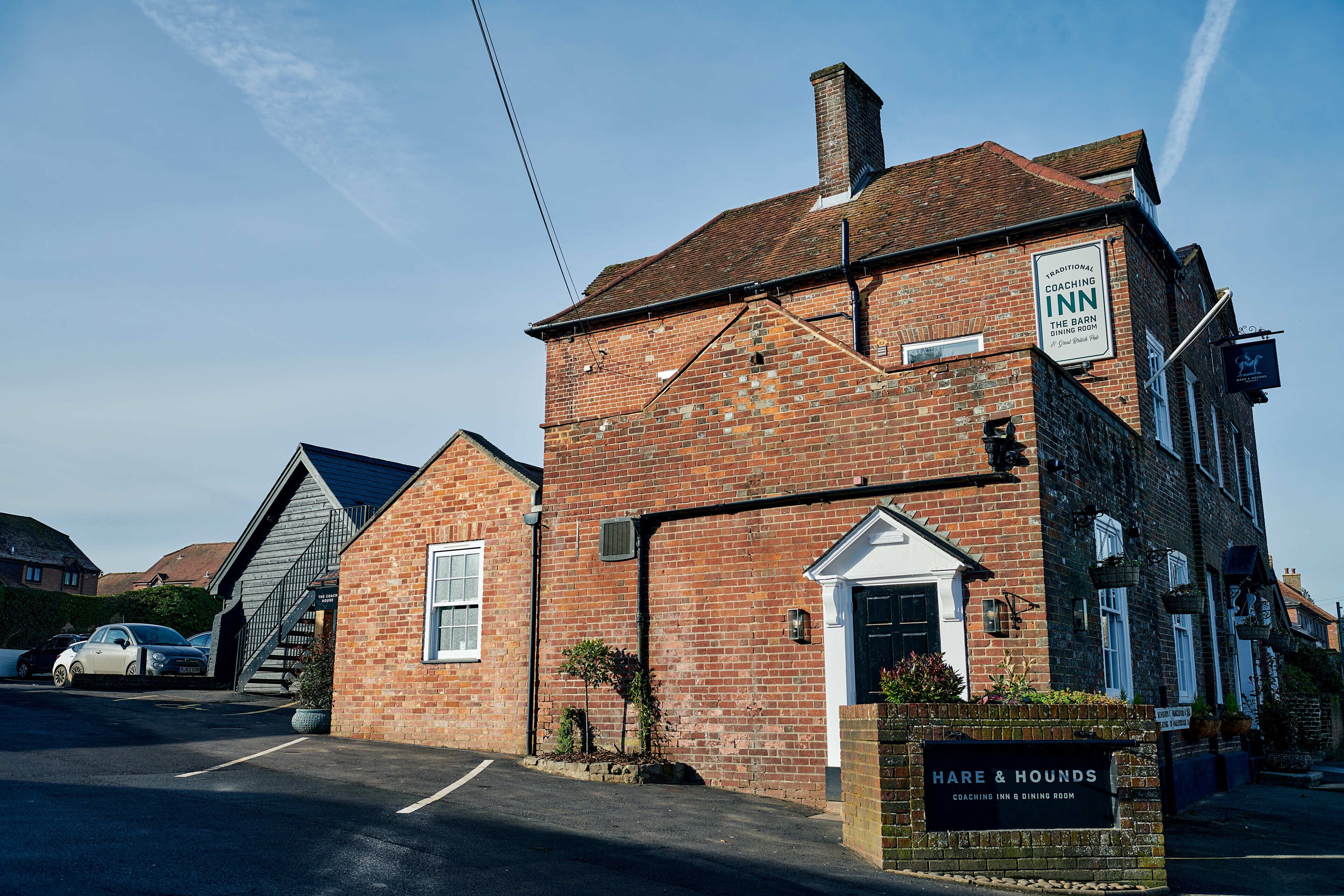 A traditional brick building with a sign for "Hare & Hounds Coaching Inn & Dining Room."