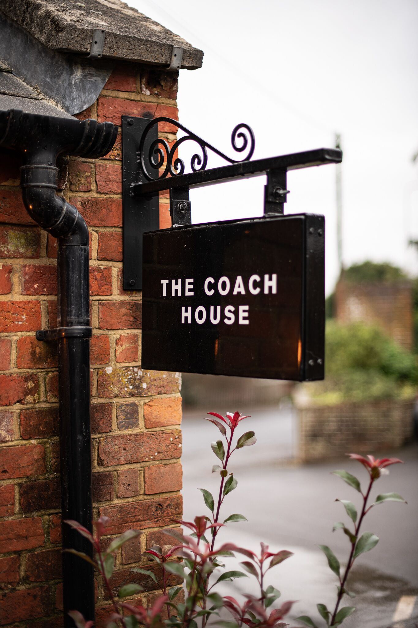 A sign for "The Coach House" mounted on a brick wall.