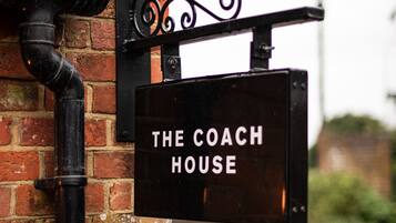 A sign for "The Coach House" mounted on a brick wall.