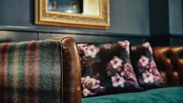 A leather armchair with a colorful blanket, a floral pillow, and a green cushion.