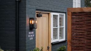 A dark grey building with a wooden door labeled "ROOMS 27, 28, 29 & 30". - Hare & Hounds Newbury (Newbury)