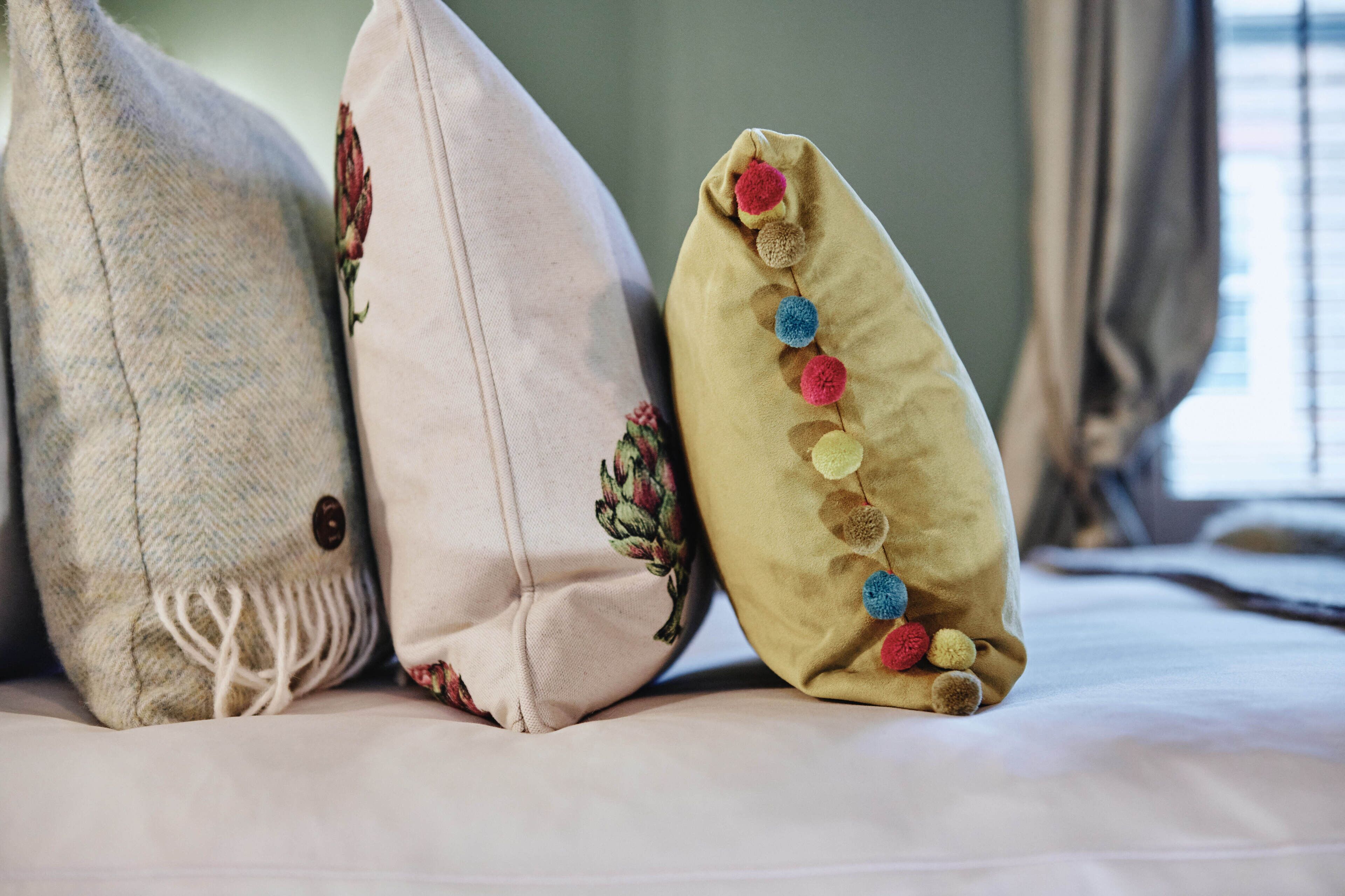 Three pillows with different textures and designs on a bed.
