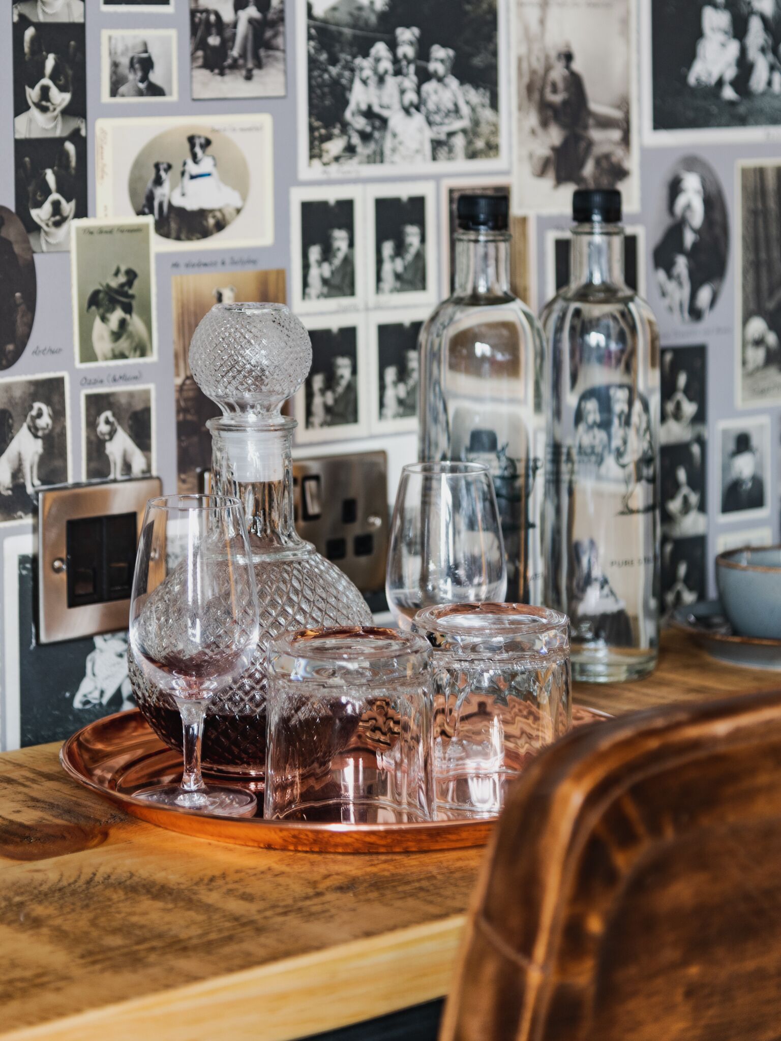 A bar area with a wooden counter, a crystal decanter, and several glasses.
