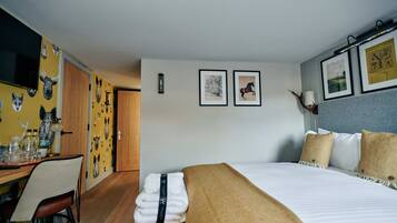 Una habitación de hotel con una cama, un escritorio con una silla y un televisor en la pared.