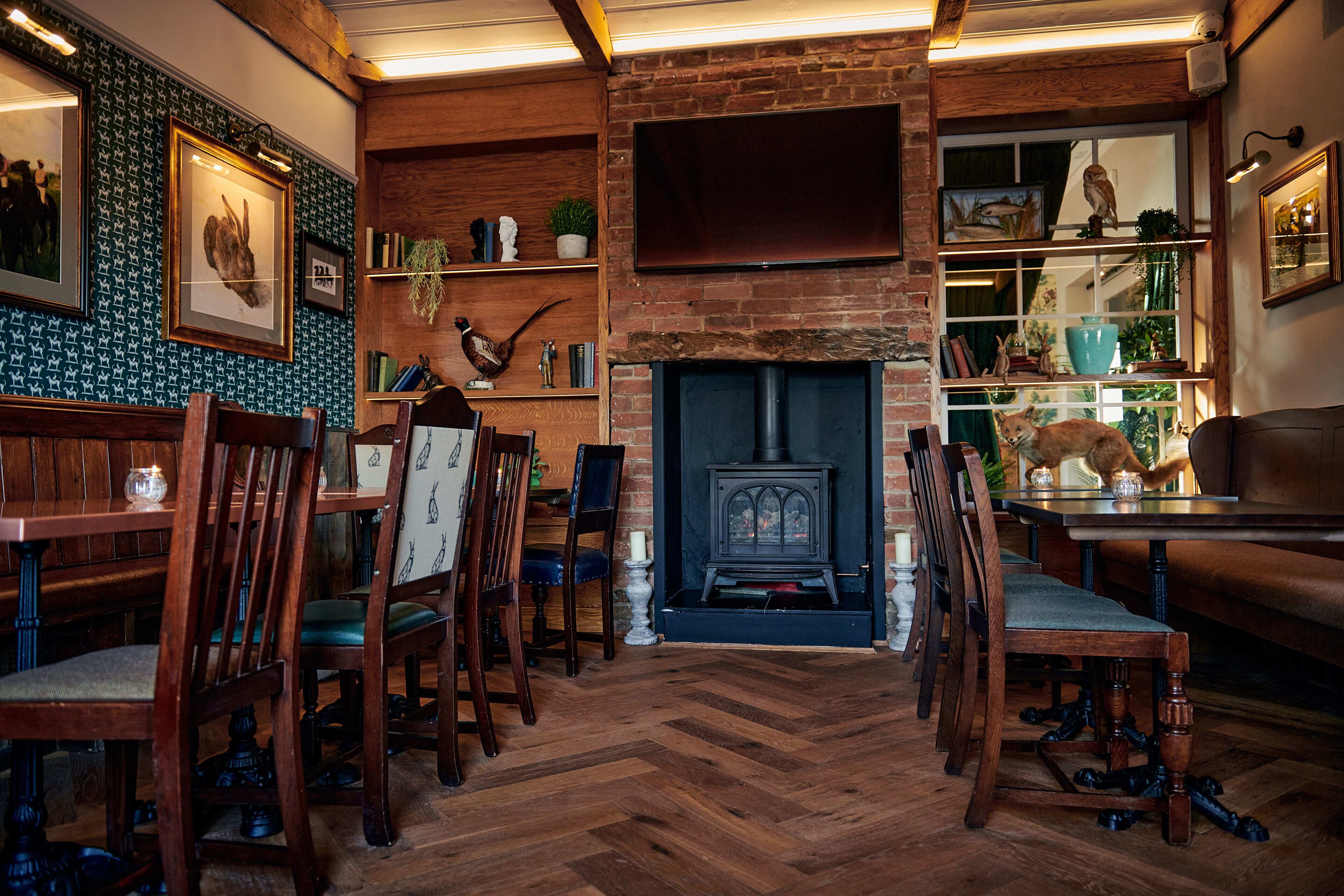 A cozy room with a fireplace, wooden furniture, and a bookshelf with various decorative items.