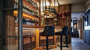 A bar area with wooden walls, a wine rack, and two leather bar stools. - Hare & Hounds Newbury (Newbury)