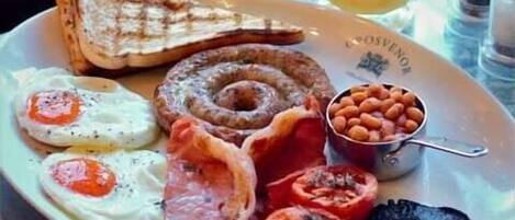 A breakfast plate with eggs, bacon, tomatoes, toast, and beans.