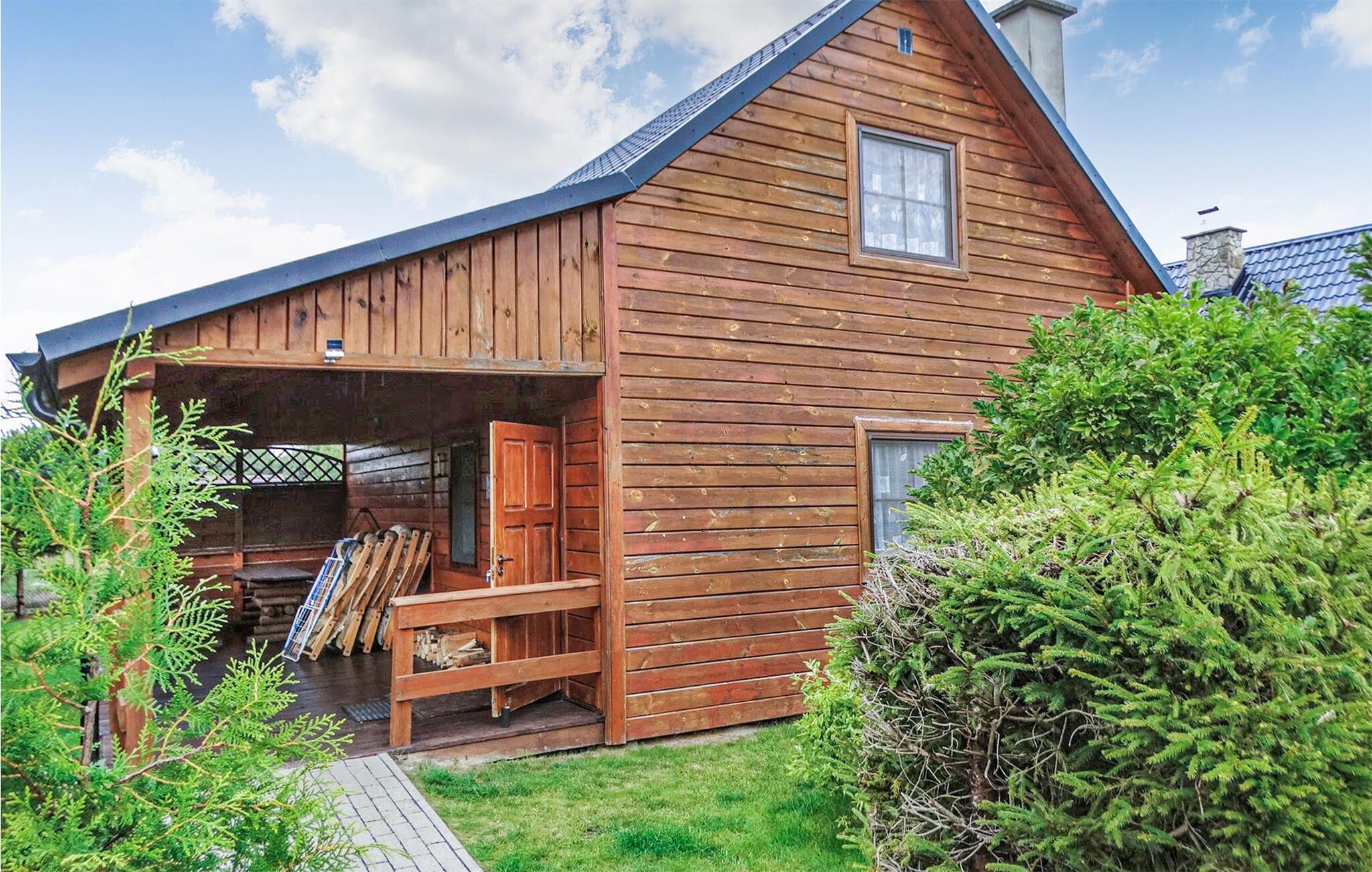 A wooden cabin with a porch, a chimney, and a small window.