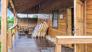 Eine Holzhütte mit verdeckter Veranda, Holzbanken und einem Metallgrill.