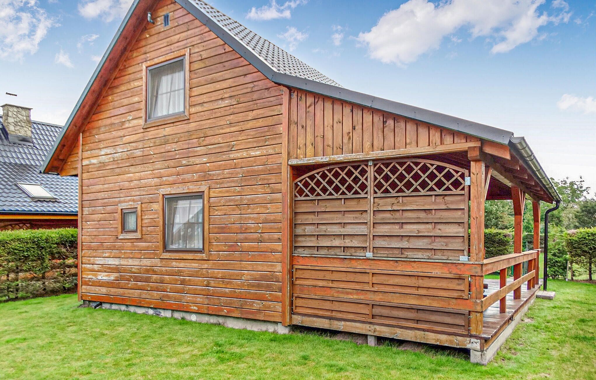Une cabane en bois avec une véranda, une petite fenêtre et une cheminée.