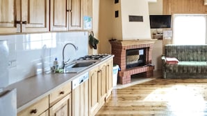 Eine Küche mit Holzschränken, einem Spülbecken, einem Herd und einem Kamin aus Ziegelsteinen.