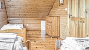 Ein Schlafzimmer einer Holzhütte mit zwei Betten, einem Schminktisch und einer Tür.