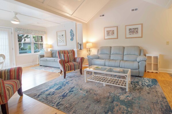 A living room with a light blue sofa, striped armchair, and a glass coffee table.