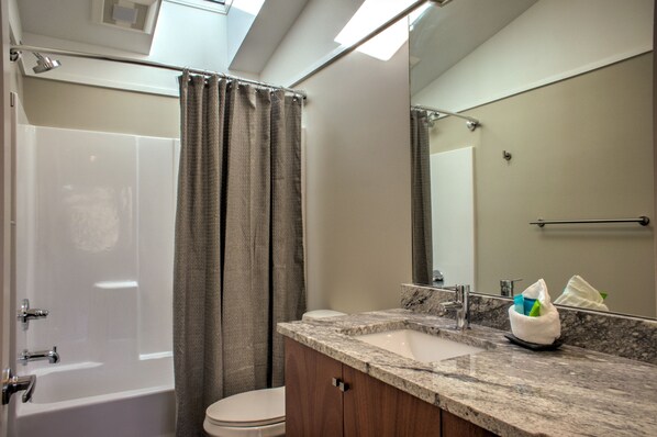 A modern bathroom with a bathtub, toilet, and vanity with a sink.