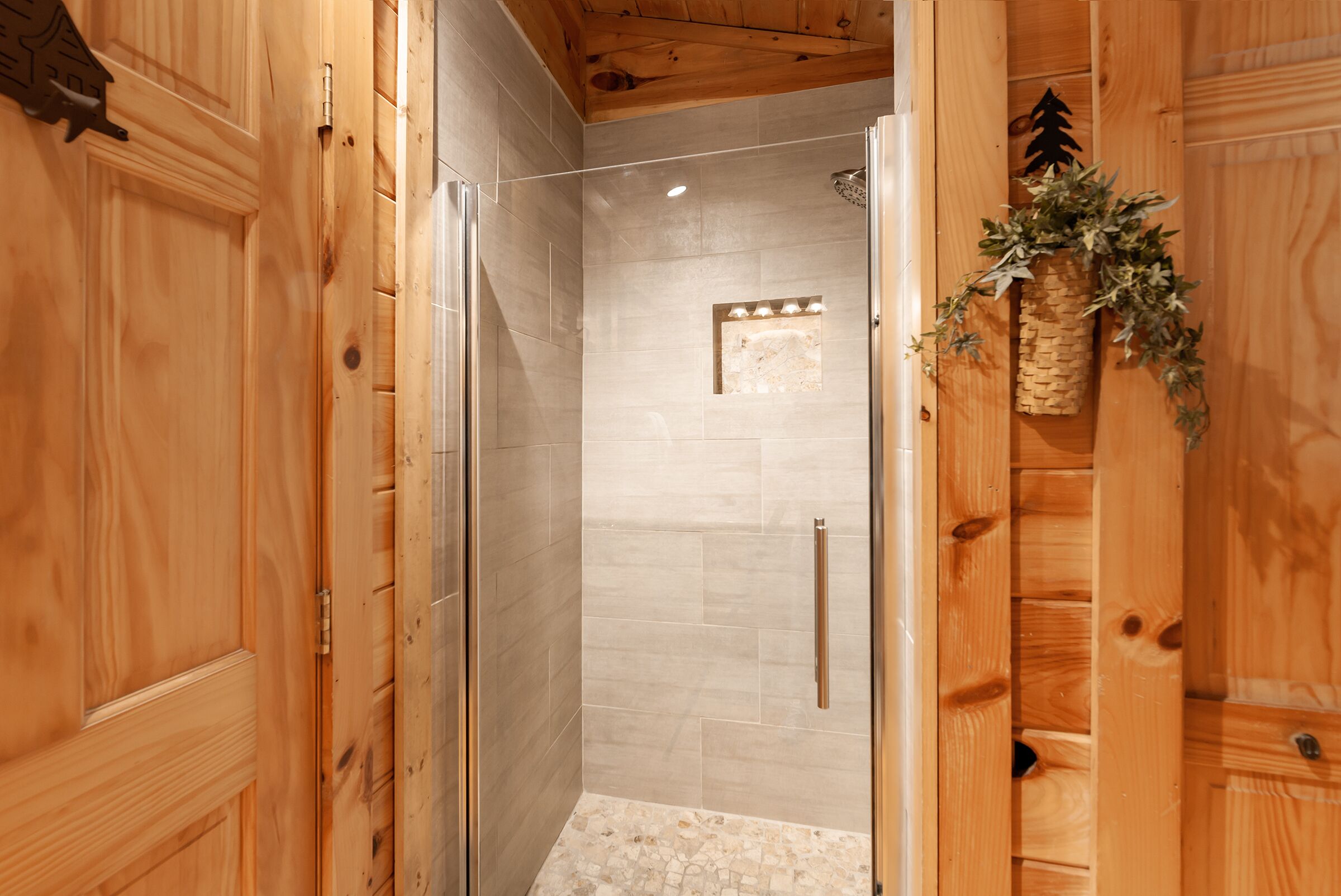 A wooden interior with a glass-enclosed shower area, wooden walls, and a small window with lights.