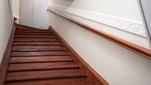 Un escalier en bois, avec un mur blanc et un décor mouluré.