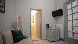 Un salon moderne avec un canapé beige, un coussin vert, un meuble blanc et un téléviseur fixé au mur.