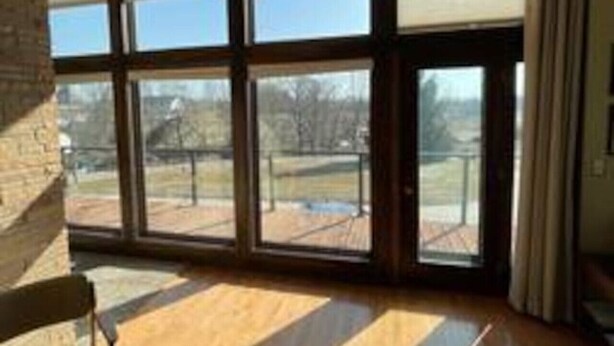 Una stanza con ampie finestre, pavimento in legno e vista su una terrazza esterna.