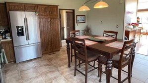 Cucina con mobili in legno, frigorifero in acciaio inossidabile e tavolo da pranzo con sedie.