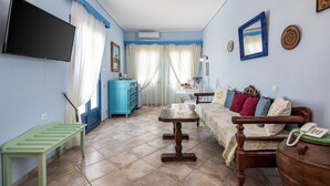 Une pièce avec une télévision, une table en bois, un canapé, une armoire bleue et un lit.