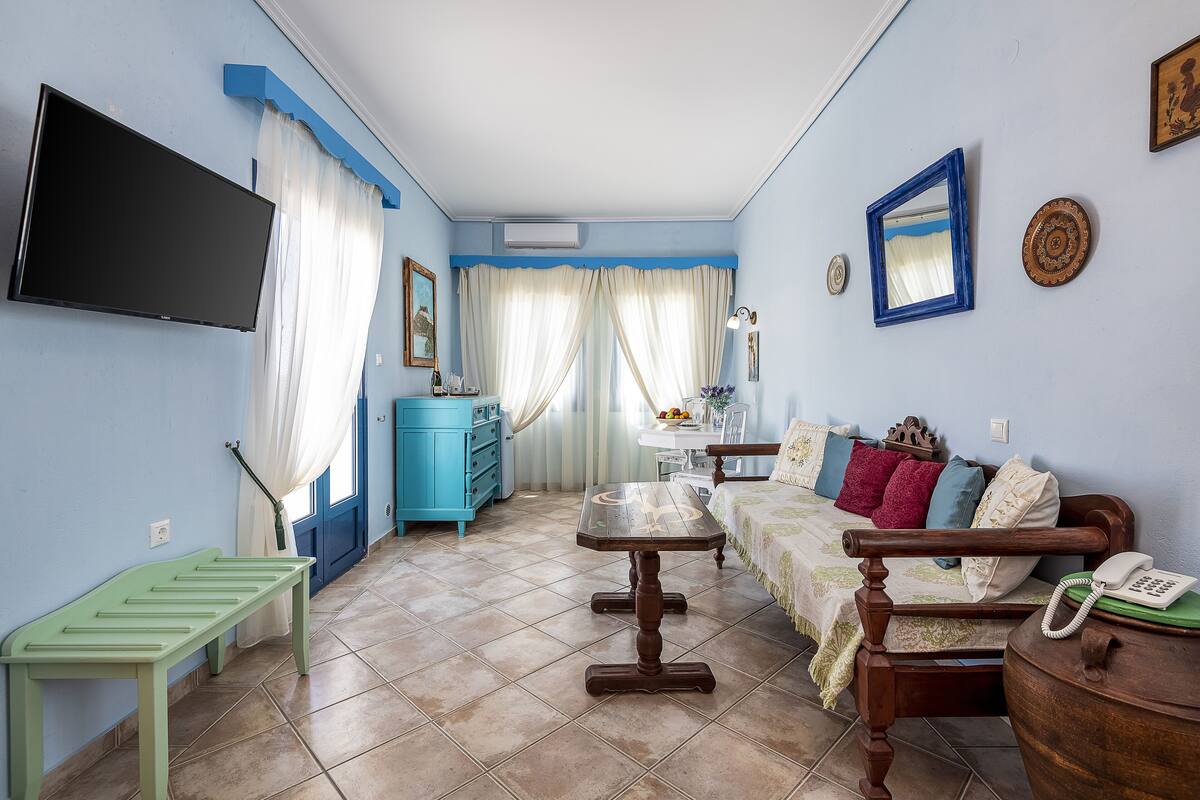 Une pièce avec une télévision, une table en bois, un canapé, une armoire bleue et un lit.