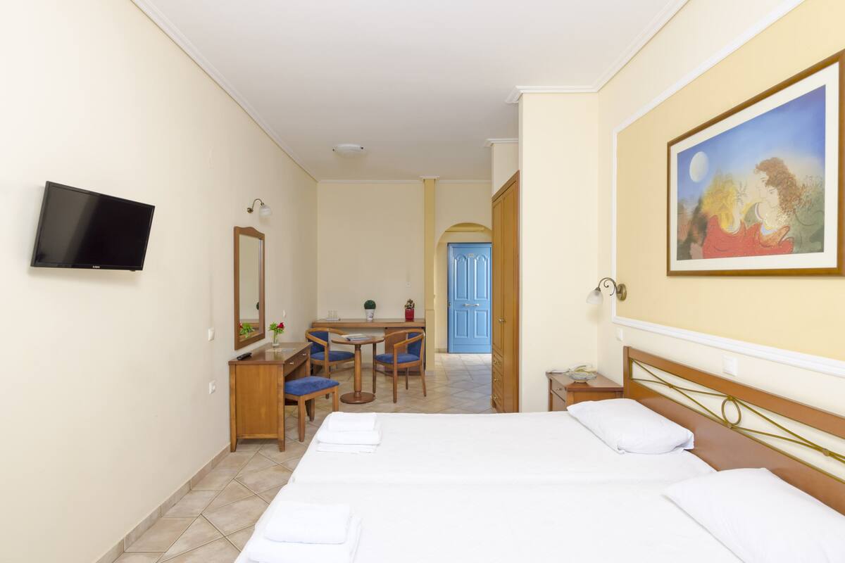 Une chambre d’hôtel avec un lit, un bureau et une chaise, une télévision et un tableau au mur.