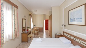 Une chambre d’hôtel avec deux lits, un bureau, une chaise, une commode et une grande fenêtre avec des rideaux.