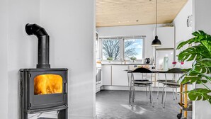 Een moderne keuken met een houtoven, een zithoek met stoelen en uitzicht op de omgeving.