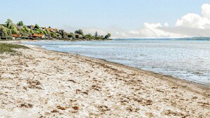 Een strand met een zandstrand en een uitzicht op huizen in de verte.