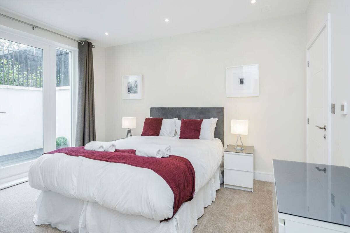 A modern bedroom with a large bed, two bedside tables, and a glass cabinet.