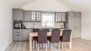 A modern kitchen with grey cabinets, a built-in oven, and a dining area with a wooden table and four chairs. - Lovely home in Masfjordnes with WiFi (Masfjordnes)