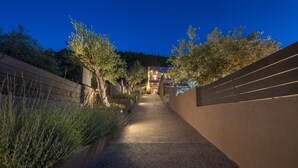A pathway leading to a building with a modern design, surrounded by trees and a landscaped area. - Anmian Suites (Sithonia)