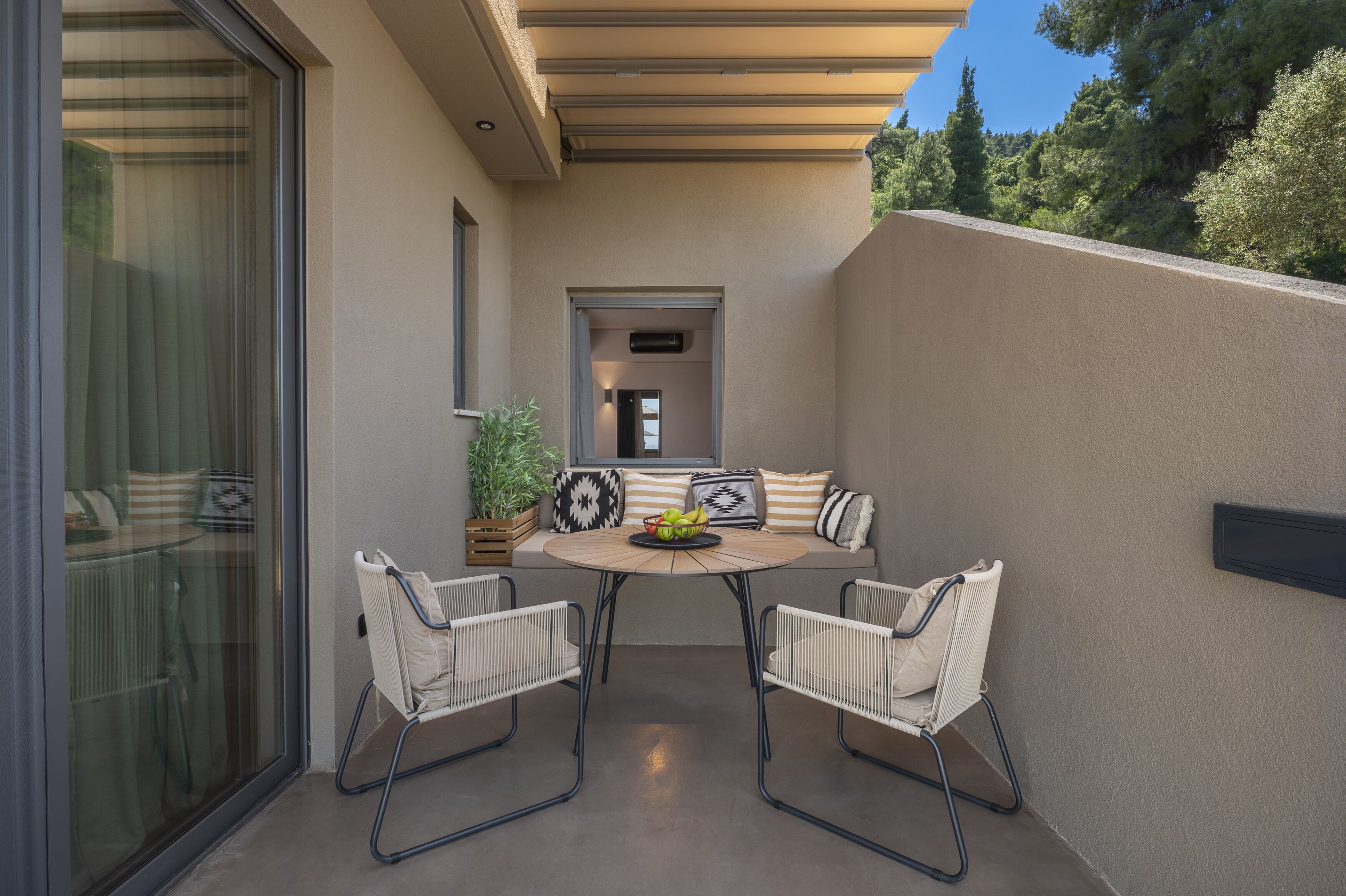 A modern outdoor seating area with a round table, two chairs, and a bowl of fruit.