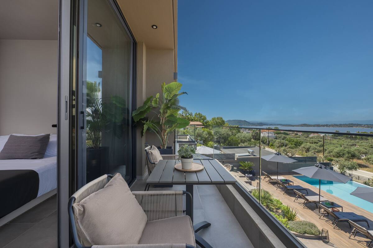 A balcony with a bed, seating area, and a pool.