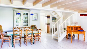 A dining area with a wooden table and chairs, a cabinet with glass doors, and a staircase leading to another level. - House for 6 in the heart of Saint Martin (Saint-Martin-de-Ré)