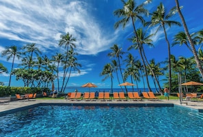 A poolside area with lounge chairs and umbrellas, palm trees, and a view of the ocean. - Beautiful Ground Floor Oasis: Workspace & Serene Surroundings -Wailea Elua 2501 (Wailea, Maui)