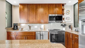 Una cocina moderna con armarios de madera, electrodomésticos de acero inoxidable, encimeras de granito y horno empotrado.