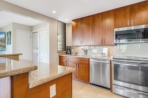 A modern kitchen with wooden cabinets, stainless steel appliances, and a granite countertop.