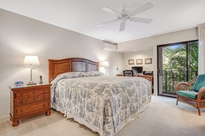 Une chambre à coucher comprenant un lit, des tables de chevet, une commode, un ventilateur de plafond, un téléviseur et un balcon avec une chaise.
