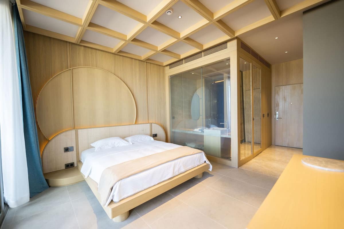 A modern bedroom with a large bed, a glass shower enclosure, and a wooden ceiling.