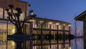 A modern building with large windows and a reflection in the water.