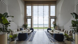 A modern living room with a large window, two sofas, a coffee table, and potted plants.