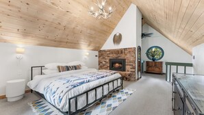 Ein Schlafzimmer mit einem Bett, einem Kamin, einer Chandelier und Blick ins Freie.
