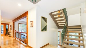 Ein geräumiger Flur mit Holzboden, einer Treppe mit grüner Geländer und einem großen Spiegel an der Wand.