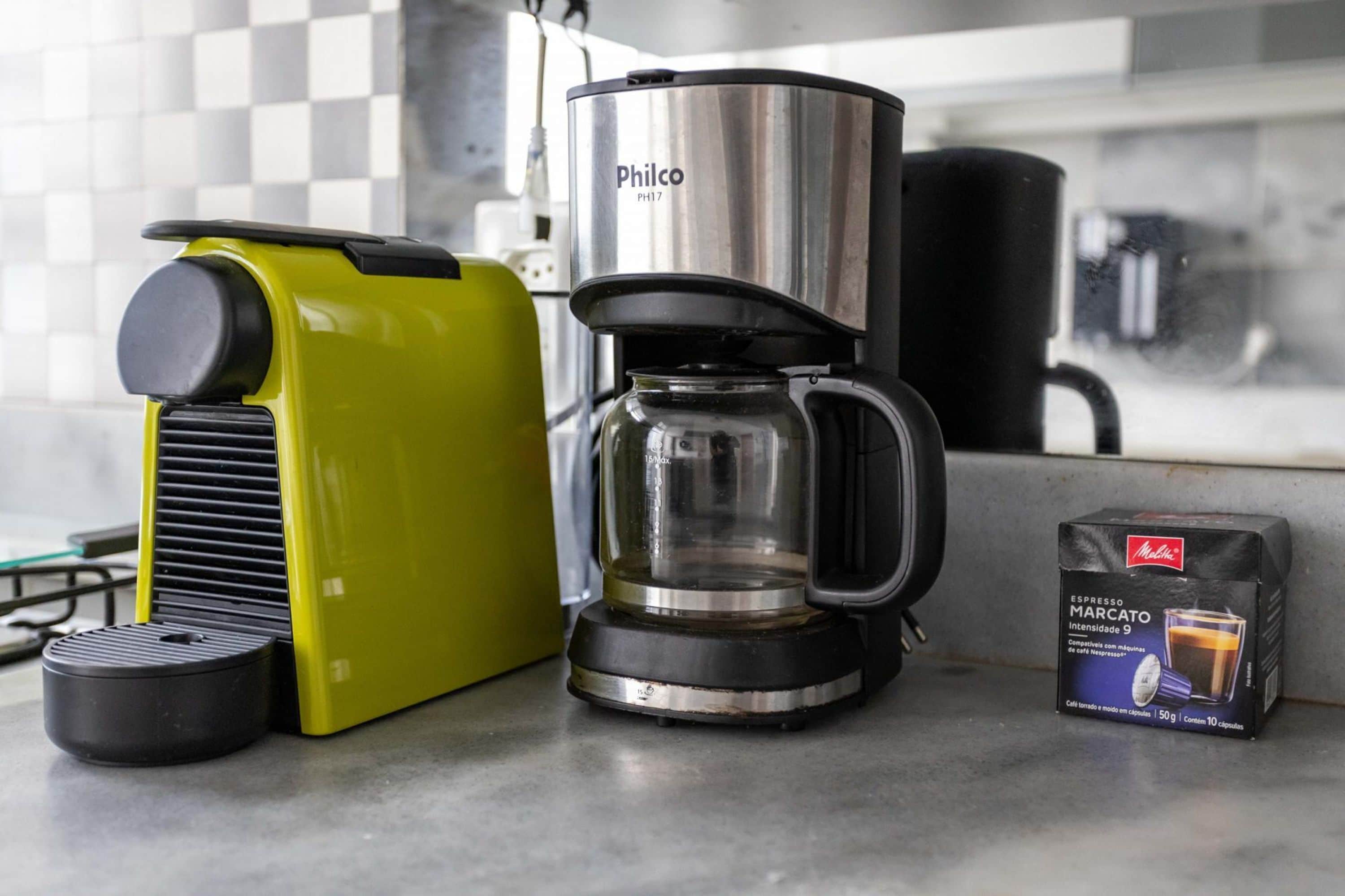A coffee maker, a coffee pot, and a box of coffee capsules on a kitchen counter.